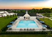 Thumbnail 31 of 44 - A large swimming pool surrounded by lounge chairs and umbrellas with a building in the background.