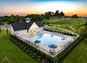 Thumbnail 22 of 44 - A pool with a white building and a black roof.