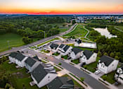 Thumbnail 16 of 44 - A sunset view of a residential area with houses and a river.