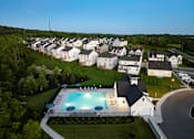 Thumbnail 20 of 44 - A swimming pool is surrounded by a grassy area and a white building.