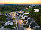 Thumbnail 17 of 44 - A sunset view of a residential neighborhood with houses and a golf course.