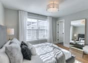Thumbnail 25 of 32 - A bedroom with a large bed and a mirror on the wall.