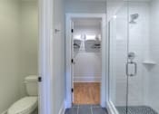 Thumbnail 31 of 32 - A white bathroom with a toilet and a walk in shower.