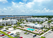 Thumbnail 46 of 47 - A large white resort with a pool and a parking lot.