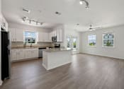 Thumbnail 22 of 47 - A spacious kitchen with white cabinets and a black refrigerator.