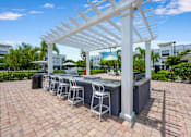 Thumbnail 37 of 47 - A white pergola is over a bar with stools.