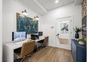 Thumbnail 11 of 47 - A room with a desk, chairs, and a painting on the wall.