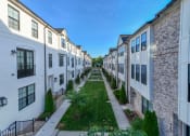 Thumbnail 20 of 23 - an alleyway between rows of white and brick apartment buildings