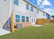 Thumbnail 28 of 30 - a white building with a yard and a wooden fence