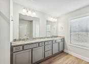 Thumbnail 17 of 50 - Primary bathroom with grey cabinets and double vanity.