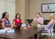 Thumbnail 22 of 38 - Business center with people sitting at the conference table at The Bartram Apartments in Gainesville, FL 32608
