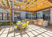 Thumbnail 5 of 38 - Courtyard pool BBQ Grill area with outdoor seating at The Bartram Apartments in Gainesville, FL 32608