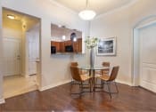 Thumbnail 32 of 38 - Dining room area located in front of kitchen bar. 4 seater round glass table pictured at The Bartram Apartments in Gainesville, FL 32608