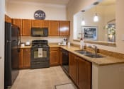 Thumbnail 30 of 38 - U shaped kitchen with black appliances at The Bartram, Gainesville, Florida 32608
