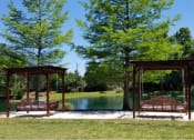 Thumbnail 14 of 38 - 2 Pergola swing beds located on top of sand box located near the pond at The Bartram Apartments in Gainesville, FL 32608