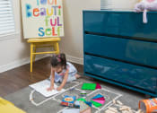 Thumbnail 38 of 38 - Toddler aged girl sitting on the bedroom floor coloring in a coloring book at The Bartram Apartments in Gainesville, FL 32608