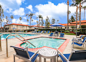 Thumbnail 6 of 30 - A pool and jacuzzi with a red pool ladder and blue pool chairs.