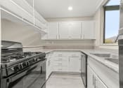 Thumbnail 10 of 15 - a kitchen with white cabinets and a black stove top oven