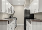 Thumbnail 11 of 15 - a kitchen with white cabinets and a black refrigerator