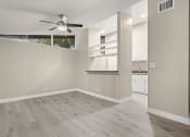 Thumbnail 9 of 15 - a bedroom with a ceiling fan and a kitchen in the background