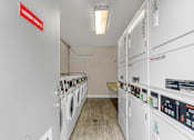 Thumbnail 44 of 44 - A laundry room with washing machines and a red sign on the wall.