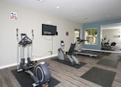 Thumbnail 19 of 29 - a gym with exercise equipment and a tv