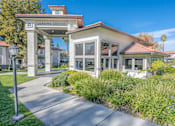 Thumbnail 11 of 30 - A leasing center is surrounded by green plants and trees.