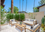 Thumbnail 2 of 15 - a patio with two couches and a coffee table in front of a concrete wall