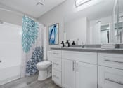 Thumbnail 11 of 20 - A bathroom with a white toilet, sink, and shower curtain.