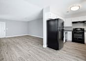 Thumbnail 17 of 21 - A kitchen with a black fridge and wooden floors.