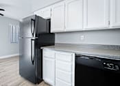 Thumbnail 19 of 21 - A black refrigerator stands next to a white oven in a kitchen.