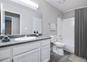 Thumbnail 12 of 21 - A bathroom with a toilet, sink, and mirror.