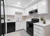 Thumbnail 12 of 15 - A modern kitchen with black appliances and white cabinets.