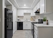 Thumbnail 1 of 15 - A modern kitchen with white cabinets and black appliances.