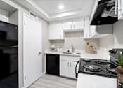 Thumbnail 14 of 15 - A modern kitchen with black appliances and white cabinets.