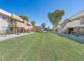 Thumbnail 14 of 20 - A row of apartment buildings with a green lawn in front.