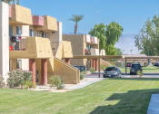 Thumbnail 17 of 20 - A building with a yellowish facade and a green lawn in front.