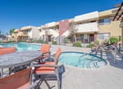 Thumbnail 18 of 20 - A pool area with chairs and a table.