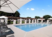 Thumbnail 1 of 25 - A pool surrounded by white umbrellas and chairs.