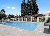 Thumbnail 4 of 25 - A large swimming pool surrounded by a concrete patio and a covered walkway.