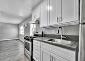 Thumbnail 7 of 17 - A kitchen with a stove, sink, and cabinets.