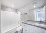 Thumbnail 40 of 42 - A white bathroom with a toilet, sink, and bathtub.