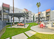 Thumbnail 26 of 42 - A sunny day at a courtyard with a palm tree, a picnic table, and a shaded area.