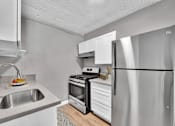 Thumbnail 3 of 17 - A modern kitchen with a stainless steel refrigerator, sink, and stove.