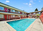 Thumbnail 1 of 17 - A swimming pool in front of a building with red doors.