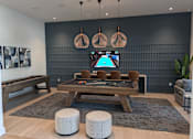 Thumbnail 24 of 30 - A room with a pool table and a TV mounted on the wall.