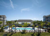 Thumbnail 16 of 29 - an aerial view of a swimming pool with palm trees in front of an apartment complex