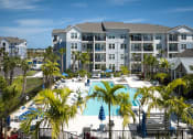 Thumbnail 12 of 29 - a large pool with palm trees in front of an apartment building
