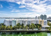 Thumbnail 4 of 28 - a large building with palm trees in front of a body of water