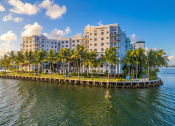 Thumbnail 6 of 28 - a group of palm trees in front of some buildings on the water